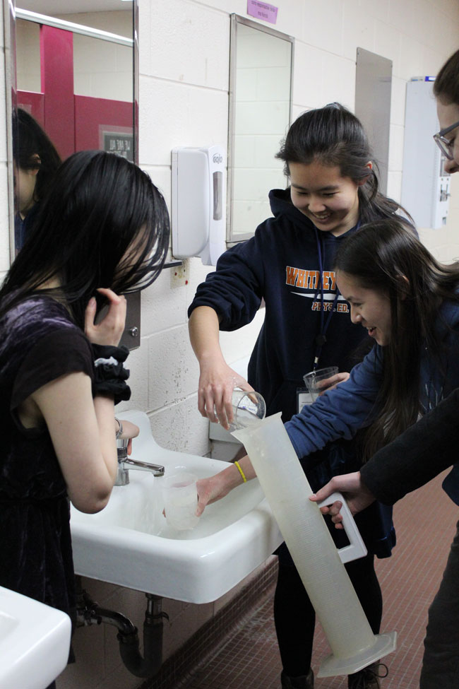 Students measure the flow rate of the faucet in a restroom on campus.